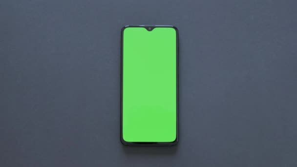 Grön skärm-en modern smartphone ligger på svart bakgrund — Stockvideo