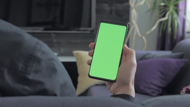 Grön skärm-man håller en smartphone. Över axeln beskådar. — Stockvideo