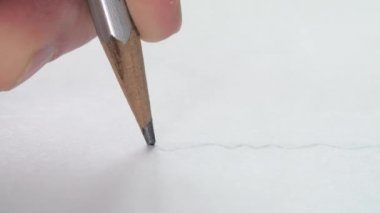 Kağıt üzerinde ahşap bir kalem ile dalgalı bir çizgi çizen sanatçıların yakın çekim.