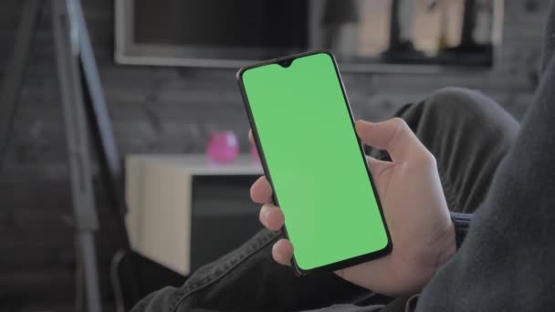 Green Screen-man thuis zittend op een bank kijken naar een smartphone. — Stockvideo