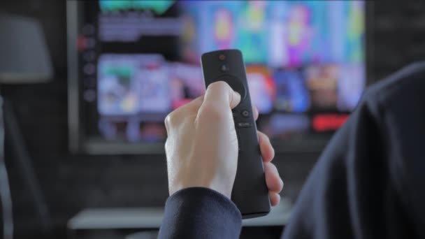 Mann hält eine Fernbedienung in der Hand und sucht nach Streaming-Medien zum Abspielen — Stockvideo