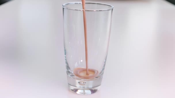 Pouring chocolate milk in drinking glass — Stock Video