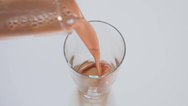 Verter leche de chocolate en el vaso de beber — Vídeo de stock