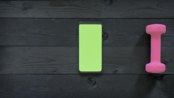 Zelená obrazovka-smartphone, vodní láhev, sluchátka a činky na stole — Stock video