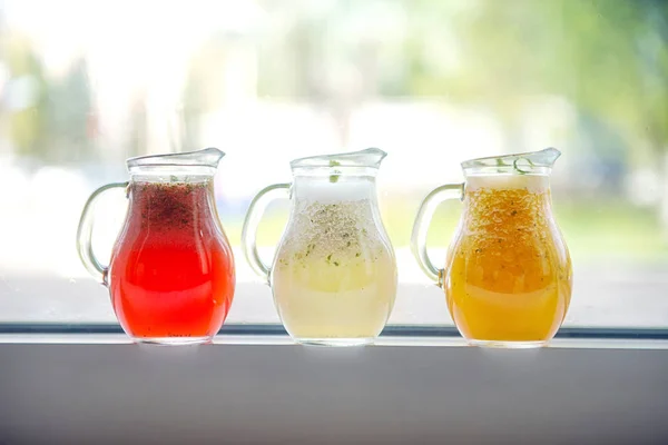 Drie soorten limonade in glazen decanters op een vensterbank op een — Stockfoto