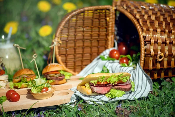 Güneşli bir günde piknik sepetinin yanında sandviç ve atıştırmalık bir şeyler..