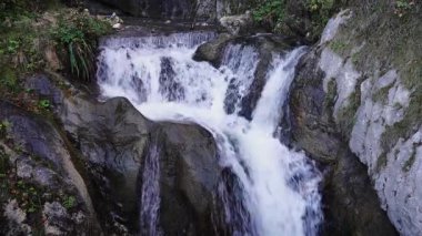 Kayaların üzerinden akan küçük şelale doğal bir derede, 4K 'da 24 fps' de ele geçirildi..