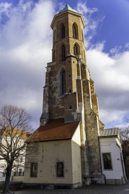 Budapeşte, Macaristan 'da bulutlu mavi gökyüzünün altındaki tarihi Buda kulesi. Yıpranmış tuğla cephesi, kemerli pencereler ve çarpıcı ışıklandırma ortaçağ mimarisini vurguluyor..