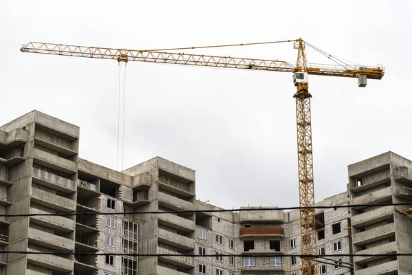 Construction crane lifts the load. Industrial work. Building a house in the city.