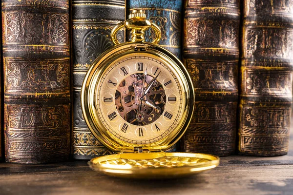 Antique clock on the background of vintage books. Mechanical clo