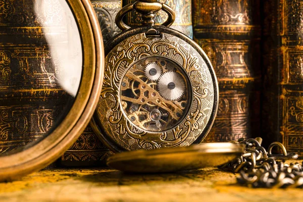 Antique clock on the background of a magnifying glass and books. — Stock Photo, Image