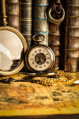Arka planda bir büyüteç ve kitap antika saat.