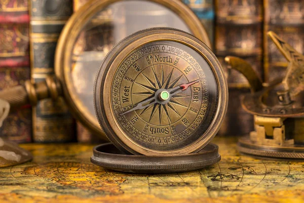Büyüteç ve kitapların arka planında antika pusula. V