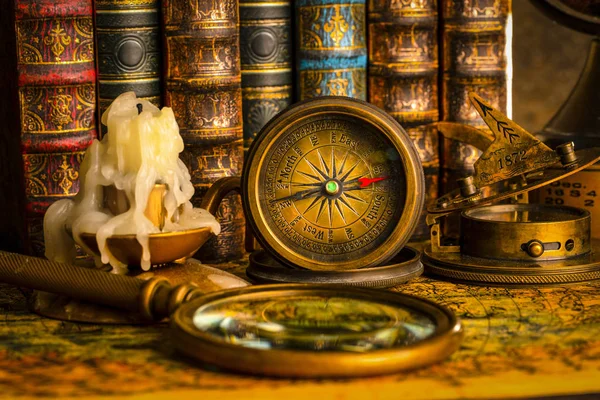 Büyüteç ve kitapların arka planında antika pusula. V