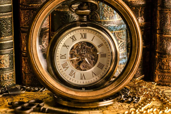 Antique clock on the background of a magnifying glass and books.