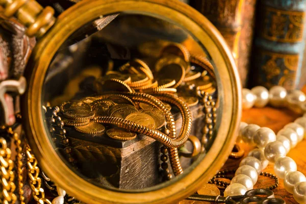 Treasure chests with gold in a magnifying glass. Pearls and gold