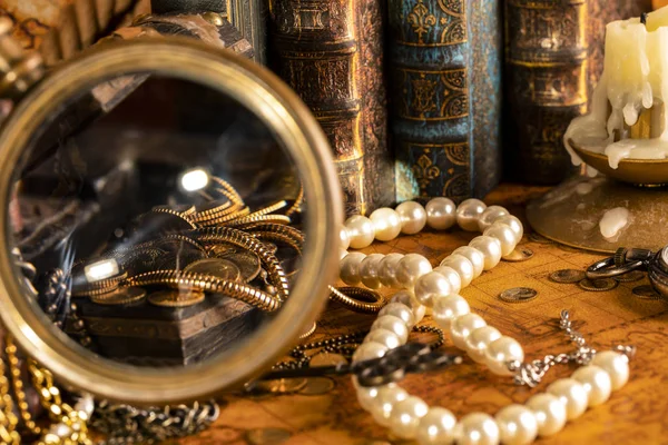 Treasure chests with gold in a magnifying glass. Pearls and gold