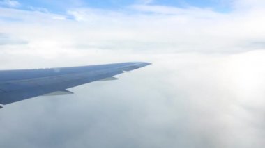 Pencereden uçağın yanından kara görünümü. Porthole'daki uçağın kanadı. Bulutların arasından.