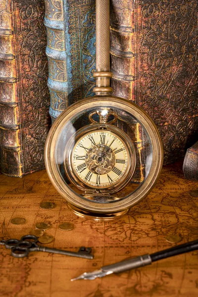 Relógio antigo no fundo de uma lupa e livros . — Fotografia de Stock