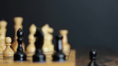 Bir adam bir şövalyenin hamlesini yapar ve piyonunu oyun alanından düşürür. Satranç tahtasının üzerinde duran satranç taşları. Proje çekimi.