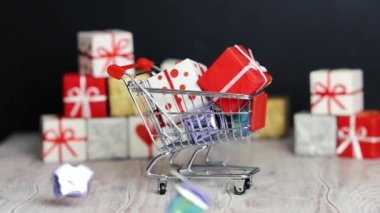 Hediyeler bir sürü hediyeler ile küçük bir oyuncak arabası üstüne düşmek. Yeni yıl hediyeleri ile dolu alışveriş sepeti. Yeni Yıl ve Noel.