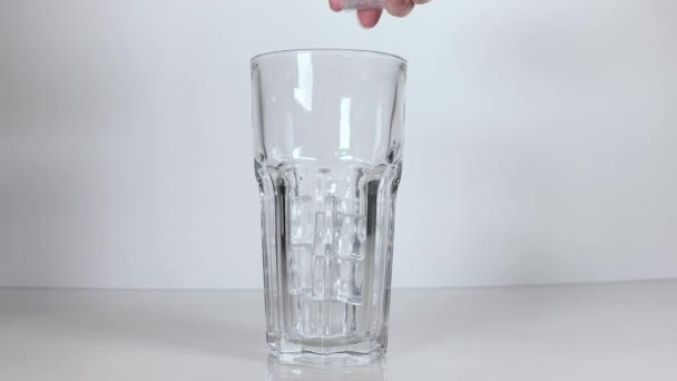 男はガラスのカップに氷のキューブを投げる — ストック動画