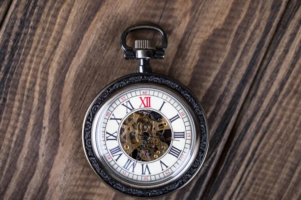 Relógio de bolso vintage em uma corrente encontram-se em uma mesa de madeira. Núm romano — Fotografia de Stock