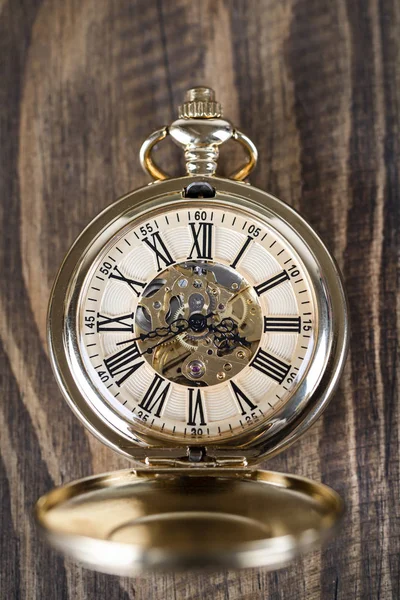 Vintage pocket watch on a chain lie on a wooden table. Roman num — Stock Photo, Image