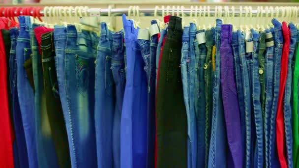 Interieur van kleding winkel. Jeans opknoping op hangers op het rek in de kleding winkel. — Stockvideo