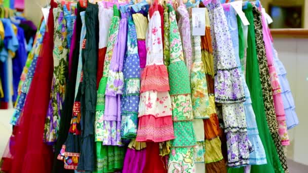 Різноманітність вішалки для одягу обертається з яскравими кольоровими модними сукнями в магазині — стокове відео