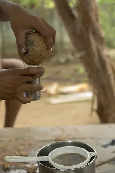 Mano ritagliata dell'uomo versando acqua di cocco in vetro argento — Foto Stock