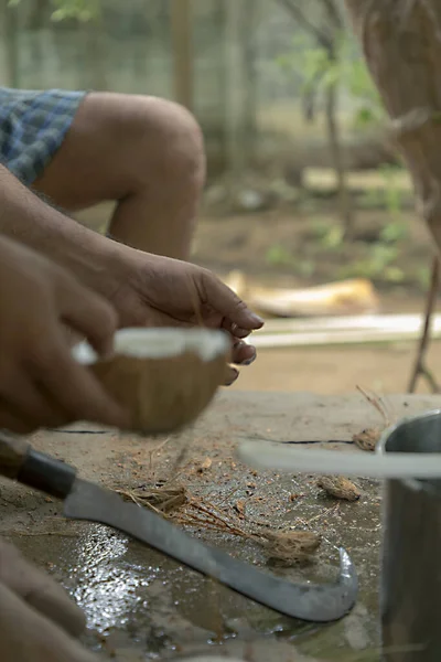 Мужчина открывает дома тропические кокосы домашним ножом — стоковое фото