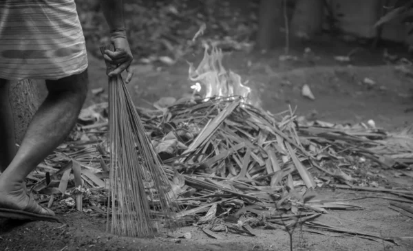 Bianco e nero - L'uomo pulisce le foglie autunnali cadute nel cortile, brucia foglie di cocco verdi e secche nel giardino con il fuoco — Foto Stock