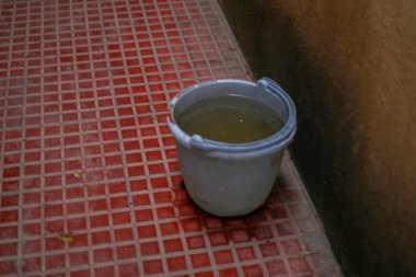 Su kavramını saklayın: Yağmur suyu koleksiyonu için zemin kahverengi turuncu plastik kova. Yağmur mevsimi yaklaşıyor..