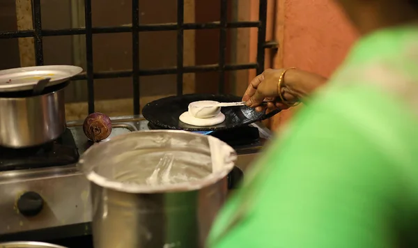 Dosa Indian food. women hand cooking or making of Dosa in kitchen, India. South Indian vegetarian, traditional and popular breakfast.