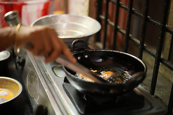 Женщина, стоящая на кухне с ложкой, готовит закуски, жареный лук бхаджи — стоковое фото