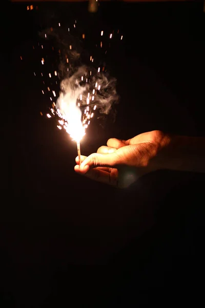 Mão segurando sparklers sobre fundo preto — Fotografia de Stock