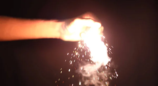 Mão segurando sparklers sobre fundo preto — Fotografia de Stock