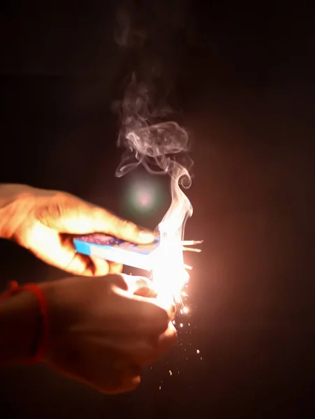 Mão segurando sparklers matchstick sobre fundo preto — Fotografia de Stock