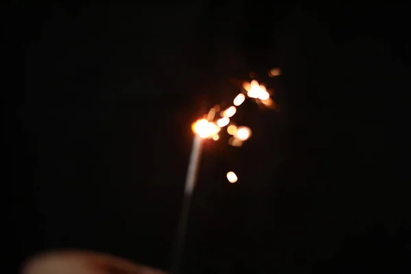 Mão segurando queima Sparkler explosão em um fundo preto — Fotografia de Stock