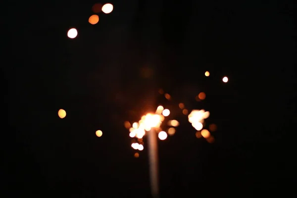 Mano sosteniendo la explosión Sparkler ardiente sobre un fondo negro — Foto de Stock