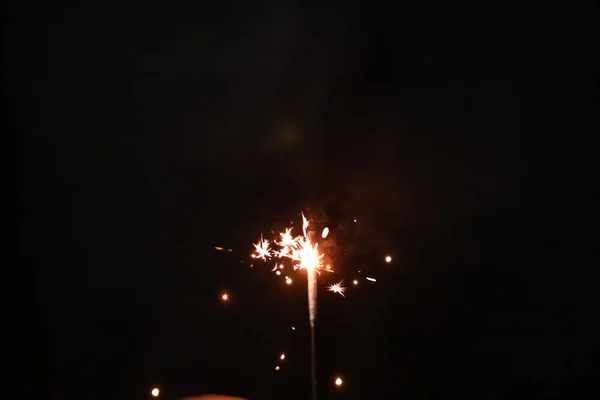 Hand holding burning sparkler blast on a black background — ストック写真