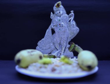Saraswathi Pooja ve Ayudha Pooja Kutlamaları - Muzlu, çiçekli ve siyah arkaplanlı gümüş heykel Murugan.