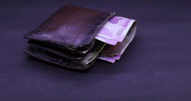Siyah arka planda Hint banknotları olan erkek çantası.