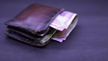 Siyah arka planda Hint banknotları olan erkek çantası.