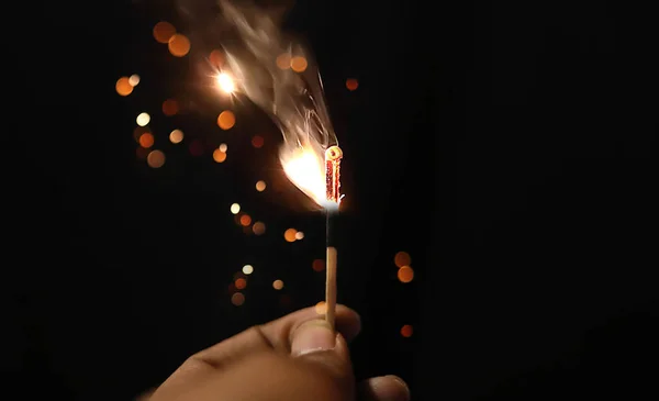 Mão segurando sparklers matchstick sobre fundo preto — Fotografia de Stock