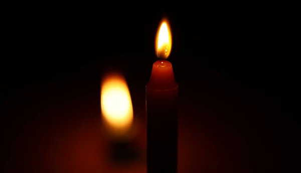 Světlo svíčky hoří jasně na černém pozadí. — Stock fotografie