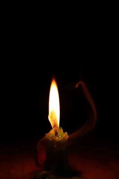 Une bougie allumée qui brûle brillamment dans le fond noir. — Photo
