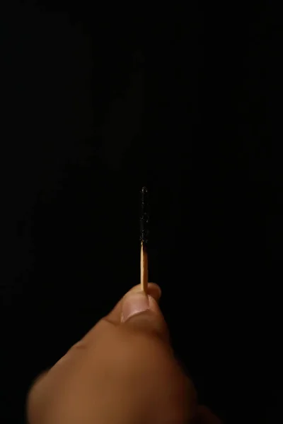 Χέρι που κρατά ένα αυτοσβηνόμενος matchstick σε μαύρο φόντο. — Φωτογραφία Αρχείου