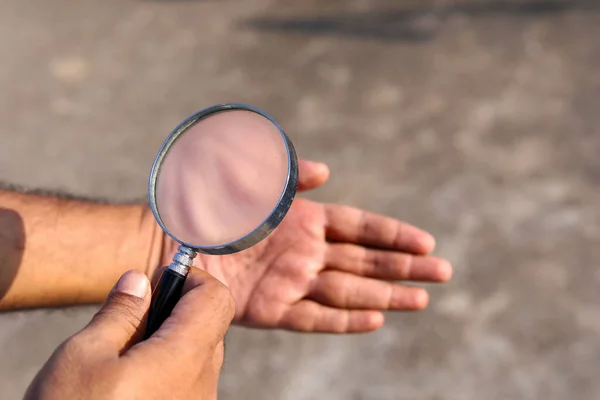 Man checks hand with magnifying glass
